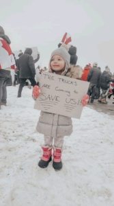 little girl holding sign the trucks are coming to save us